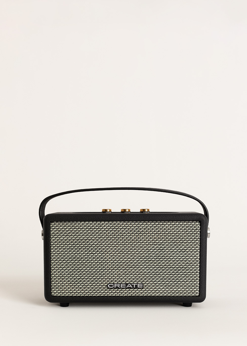Un altavoz rectangular en blanco y negro con asa. Perillas doradas en la parte superior y la palabra CREATE al frente.