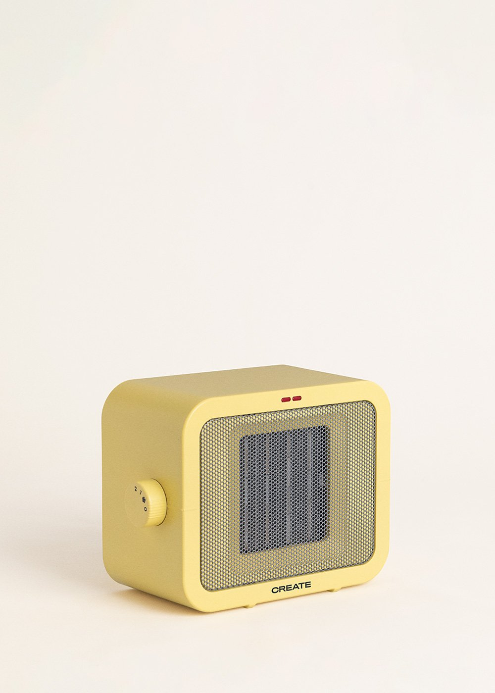 Un calefactor cuadrado amarillo con una rejilla frontal, un dial y dos luces rojas, sobre un fondo blanco. La palabra CREATE es visible.