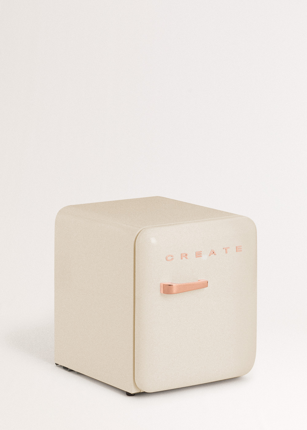 Un mini-frigorífico color crema con la palabra 'CREATE' en oro rosa. Tiene un tirador de oro rosa y está sobre un fondo blanco.