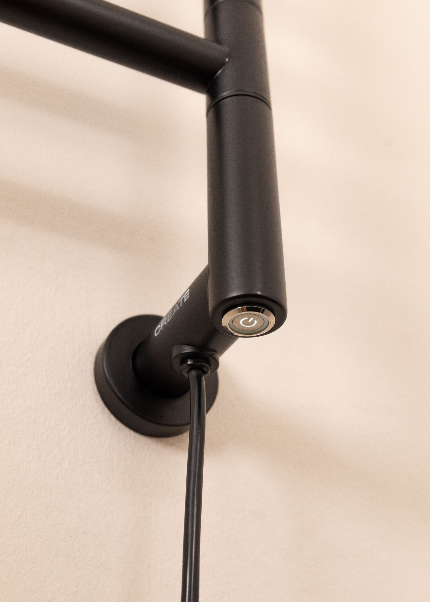 Primer plano de un dispositivo negro montado en la pared con un botón de encendido. El dispositivo está etiquetado como 'CREATE' y tiene un cable de alimentación.