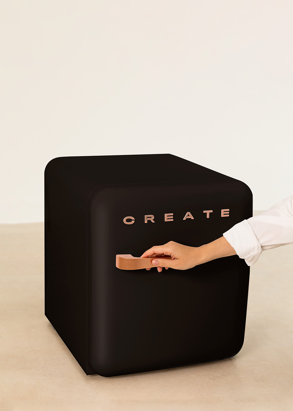 Una mini nevera negra con la palabra CREATE. Una mano abre la manija. El fondo es color crema.