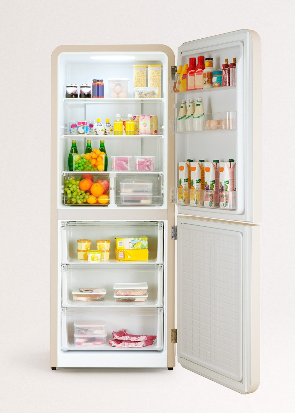 Un refrigerador beige abierto, lleno de alimentos: frutas, verduras, bebidas y artículos envasados. Está bien organizado.