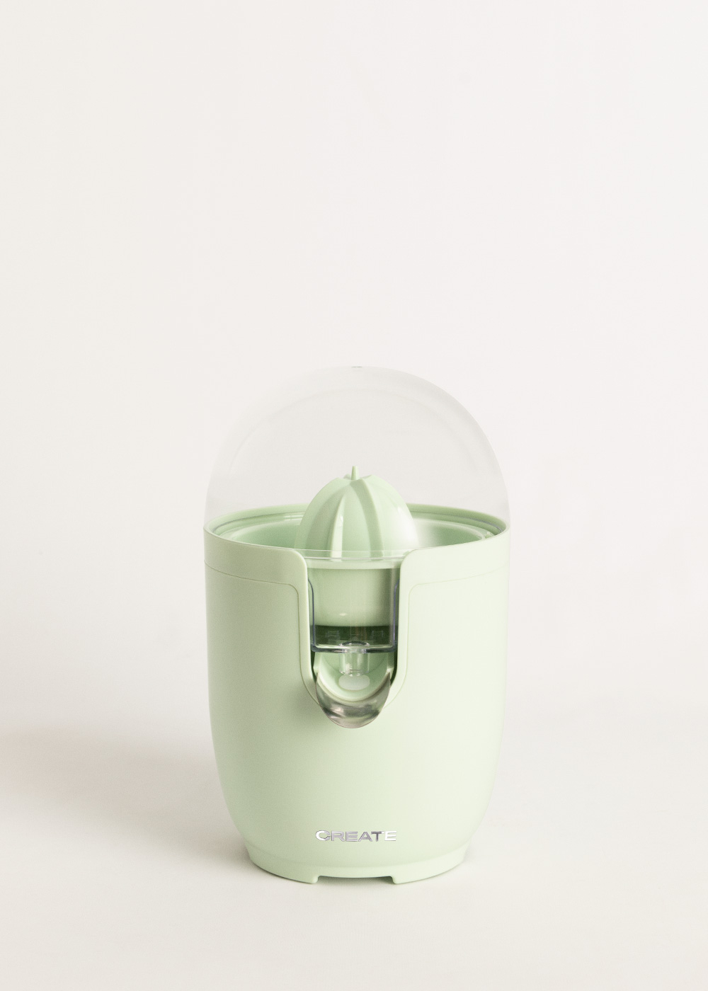 Un exprimidor de cítricos verde menta con una cubierta de cúpula transparente, sobre un fondo blanco. La palabra 'CREATE' es visible.