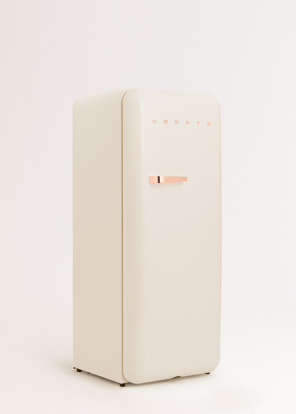 Un refrigerador crema con manija de cobre, la palabra CREATE está arriba. Se encuentra sobre un fondo blanco.