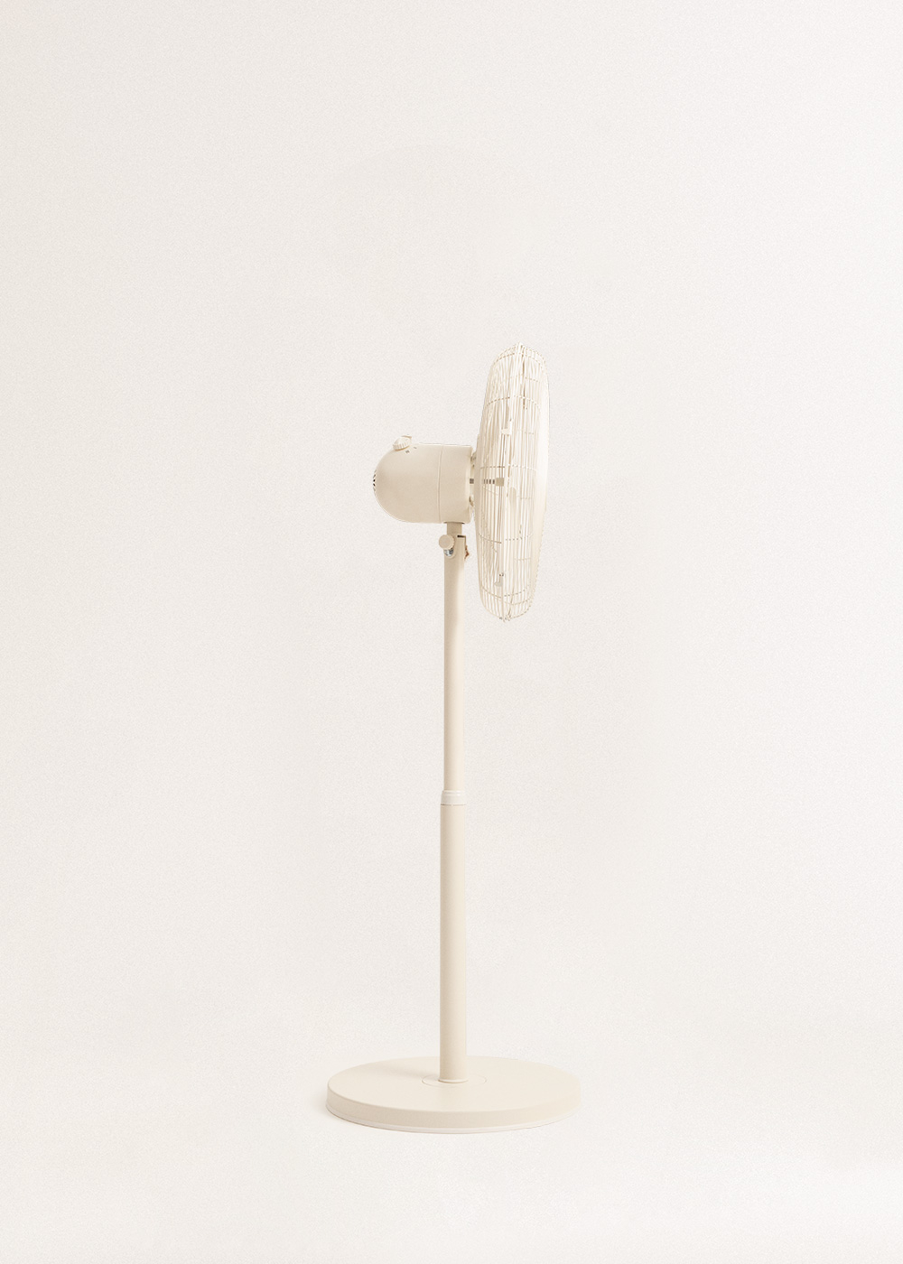 Un ventilador de pie color crema está centrado sobre un fondo blanco. El ventilador está girado hacia un lado, con las aspas visibles.