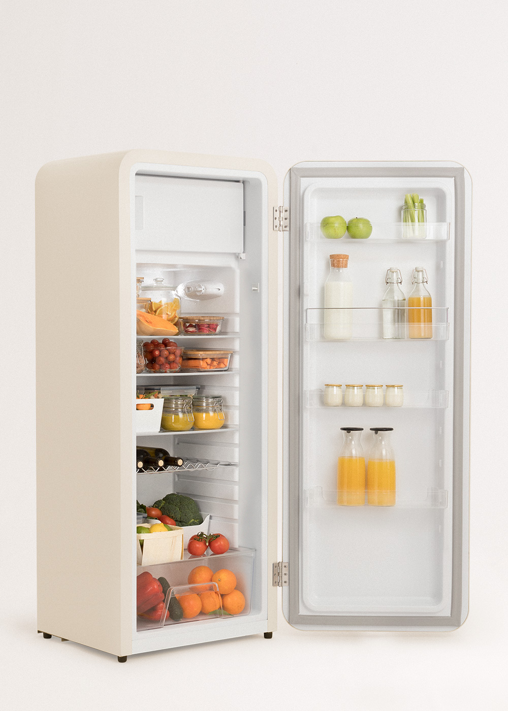 Refrigerador beige abierto lleno de frutas, verduras, jugo y lácteos. Se ven manzanas, naranjas y tomates.