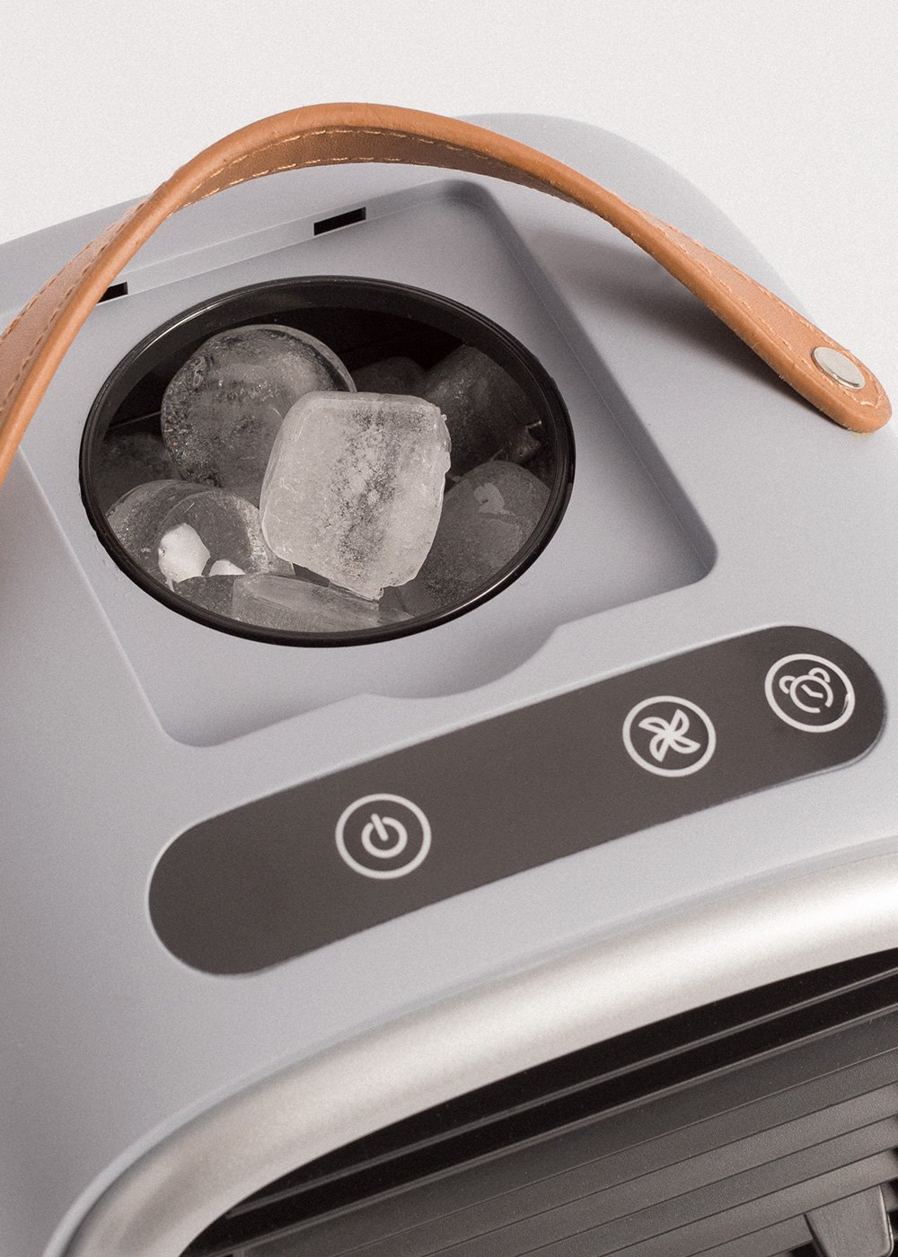 Una máquina de hielo con asa de cuero. Cubitos de hielo visibles en el recipiente. Panel de control con símbolos abajo.