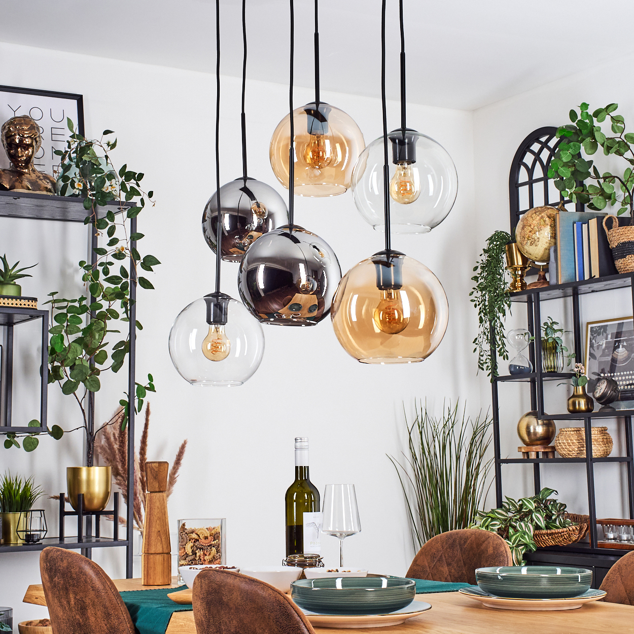 Esszimmer mit Holztisch, Hängelampen und Regalen mit Dekoration. Teller, Wein und Stühle sind ebenfalls sichtbar.