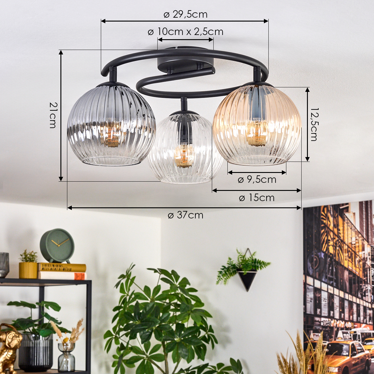 Moderne Deckenlampe mit drei Glasschirmen. Abmessungen sind angegeben. Hintergrund zeigt Pflanzen, Uhr und Stadtkunst.