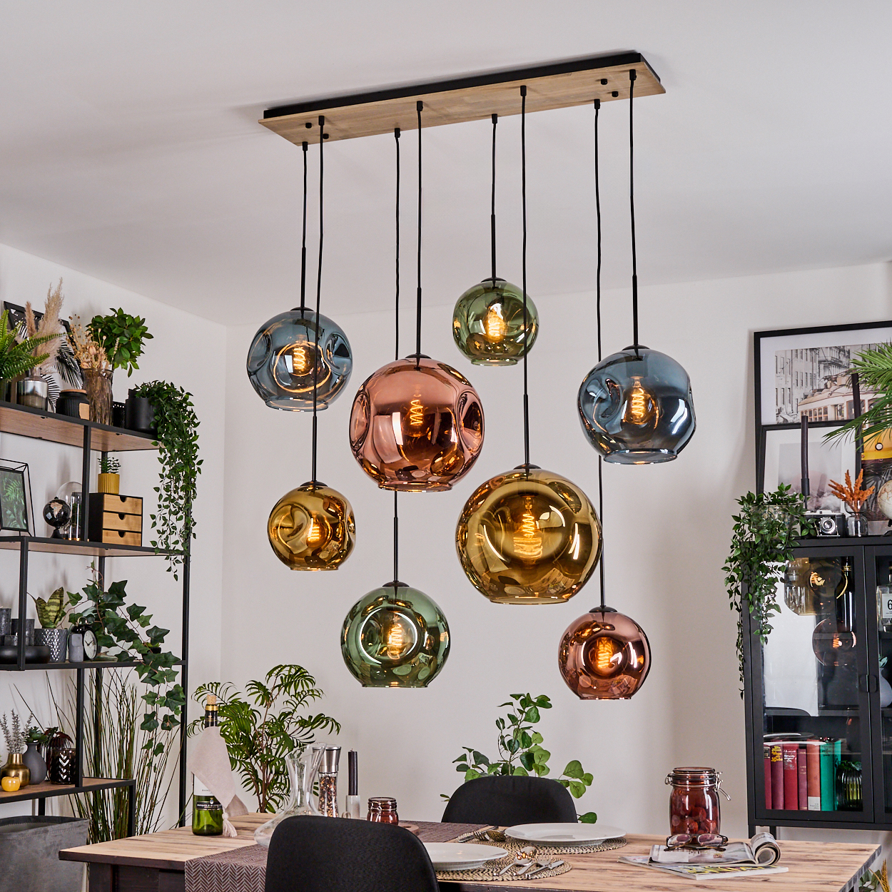 Esszimmer mit bunten Glaskugellampen. Ein Holztisch ist mit Tellern und Stühlen gedeckt.