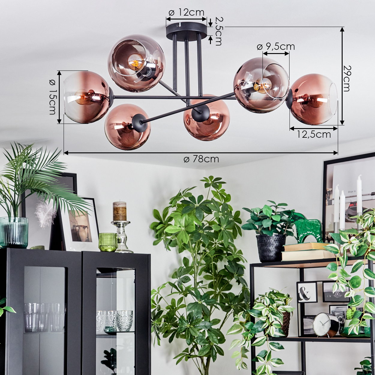 Eine moderne Deckenlampe mit sechs Kugellampen hängt. Darunter ein Raum mit Pflanzen, einem schwarzen Schrank und einem Regal.