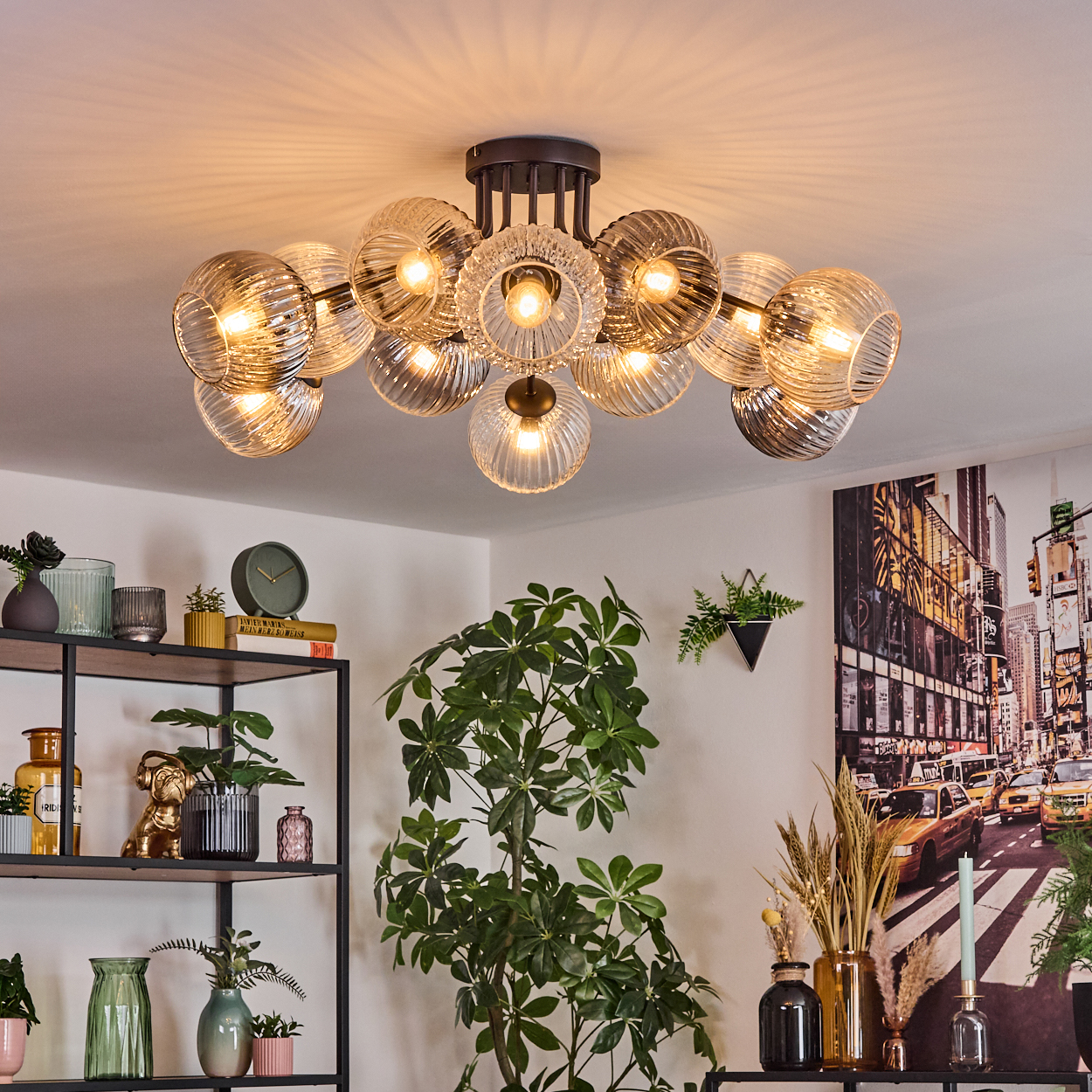 Ein modernes Wohnzimmer mit einem großen Blasen-Kronleuchter. Bücherregale und Pflanzen im Vordergrund, eine Stadtlandschaft im Hintergrund.