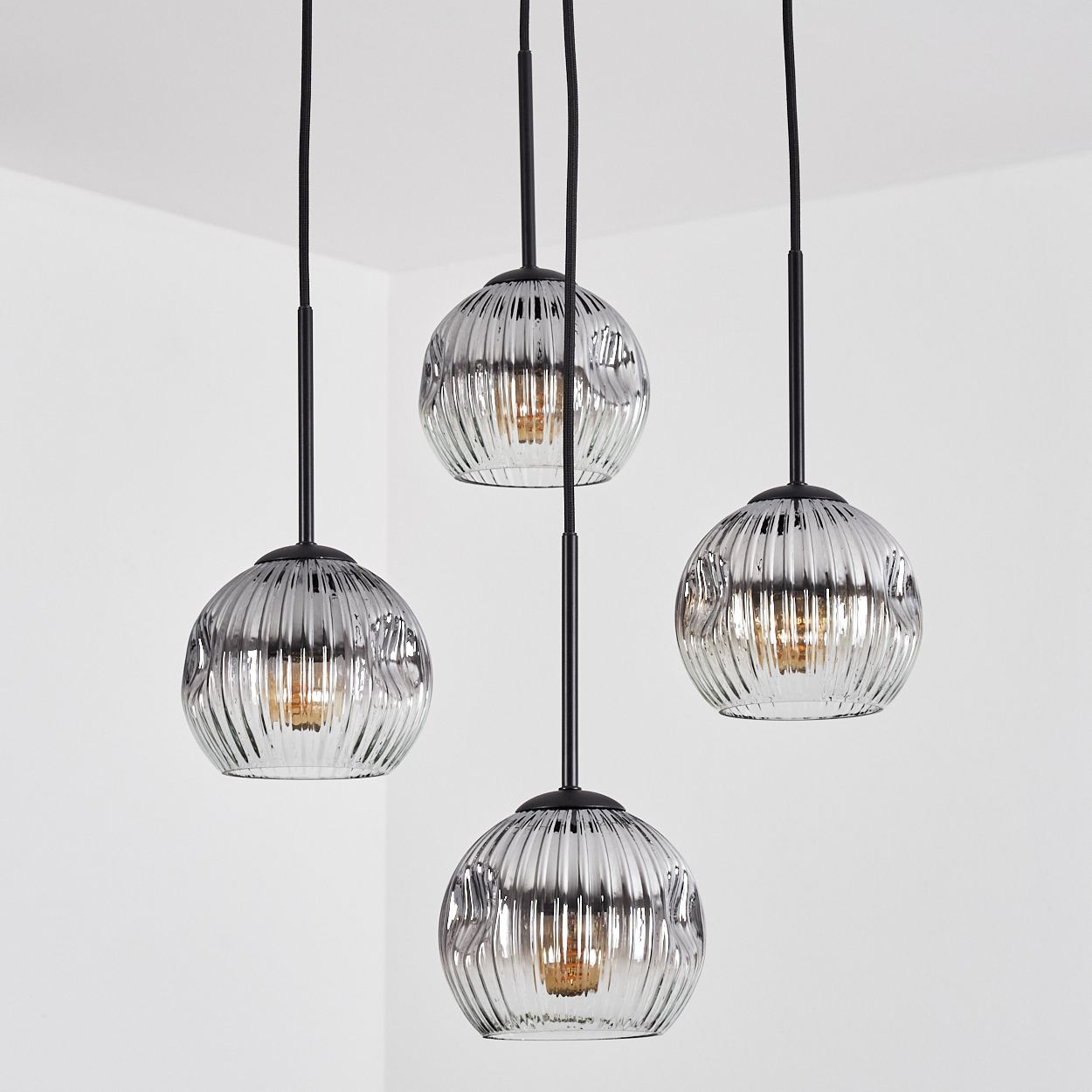 Vier Glaskugel-Pendelleuchten hängen von der Decke. Die Kugeln sind geriffelt und silberfarben, mit sichtbaren Glühbirnen.