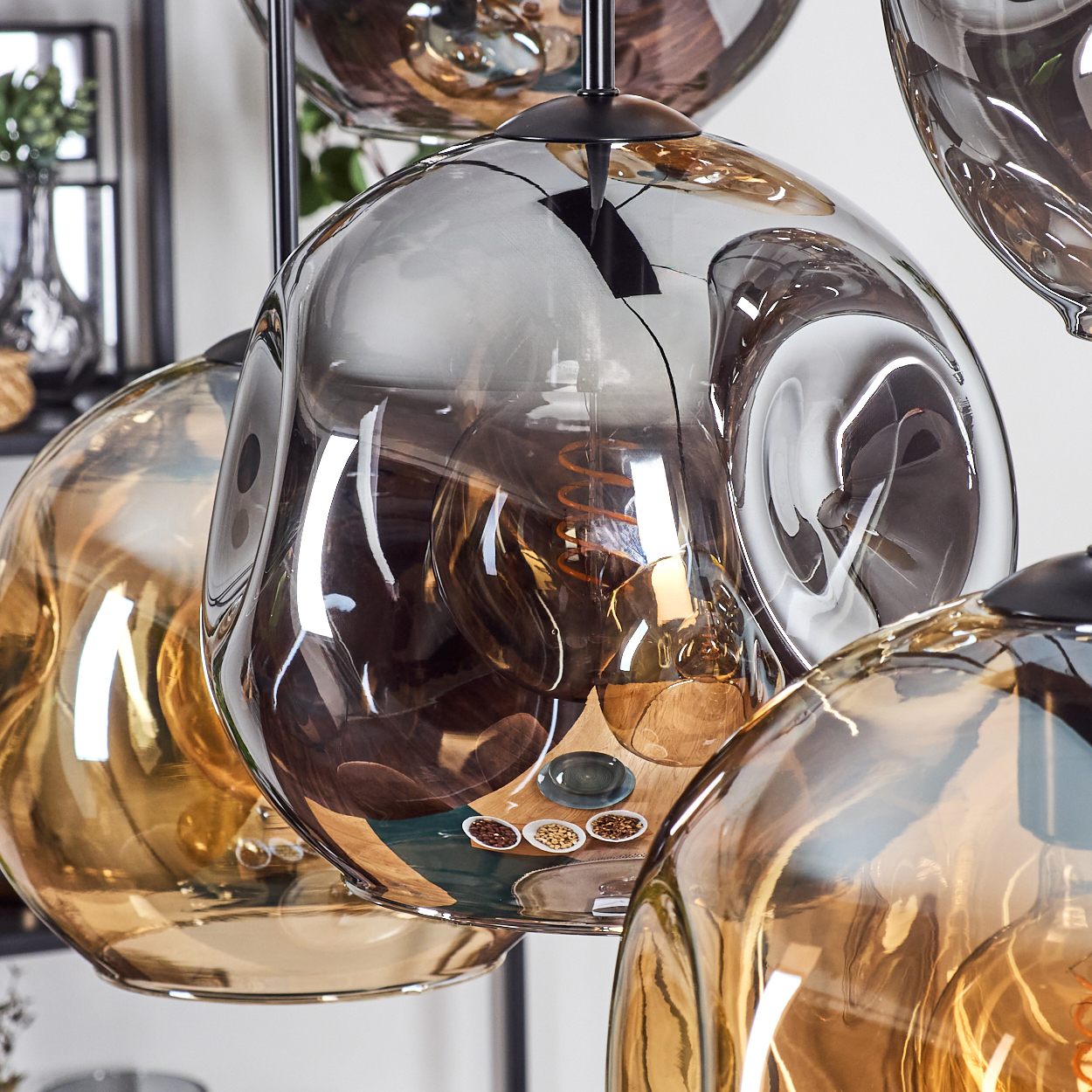 Nahaufnahme von Glas-Pendelleuchten. Glühbirnen innen, mit braunen und grauen Farbtönen. Hintergrund: Regal und Dekoration.
