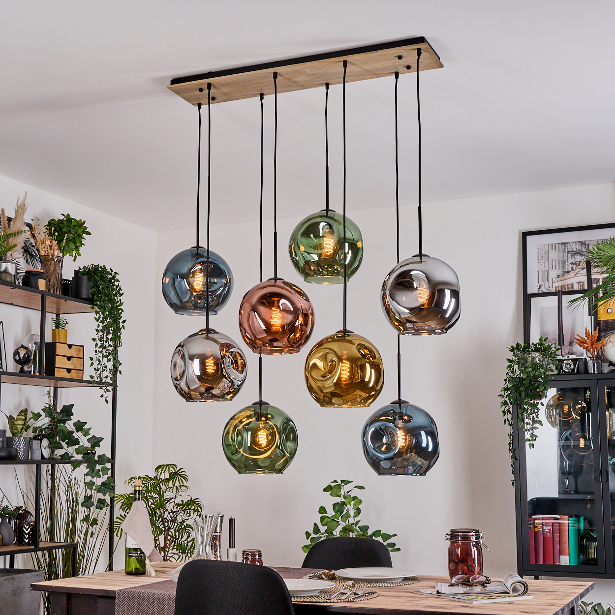Esszimmer mit Holztisch, Hängelampen mit farbigen Glaskugeln und dekorativen Regalen mit Pflanzen.