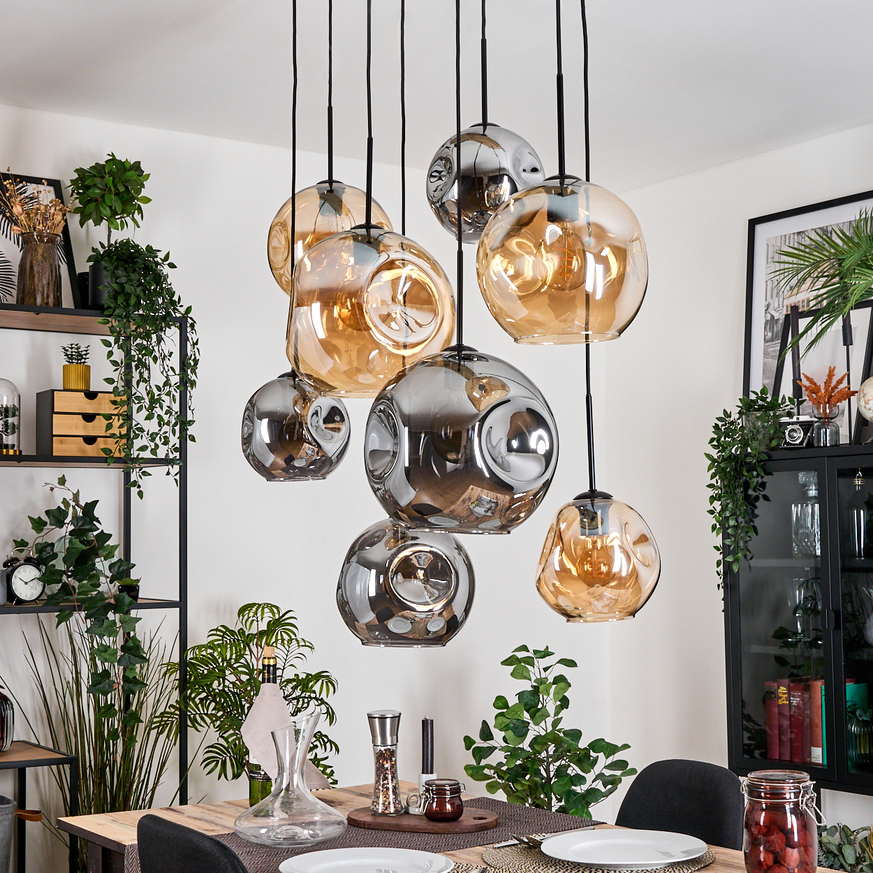 Esszimmer mit hängenden Glaskugelleuchten. Pflanzen und Dekorationen sind im Hintergrund zu sehen, auf einem Holztisch.