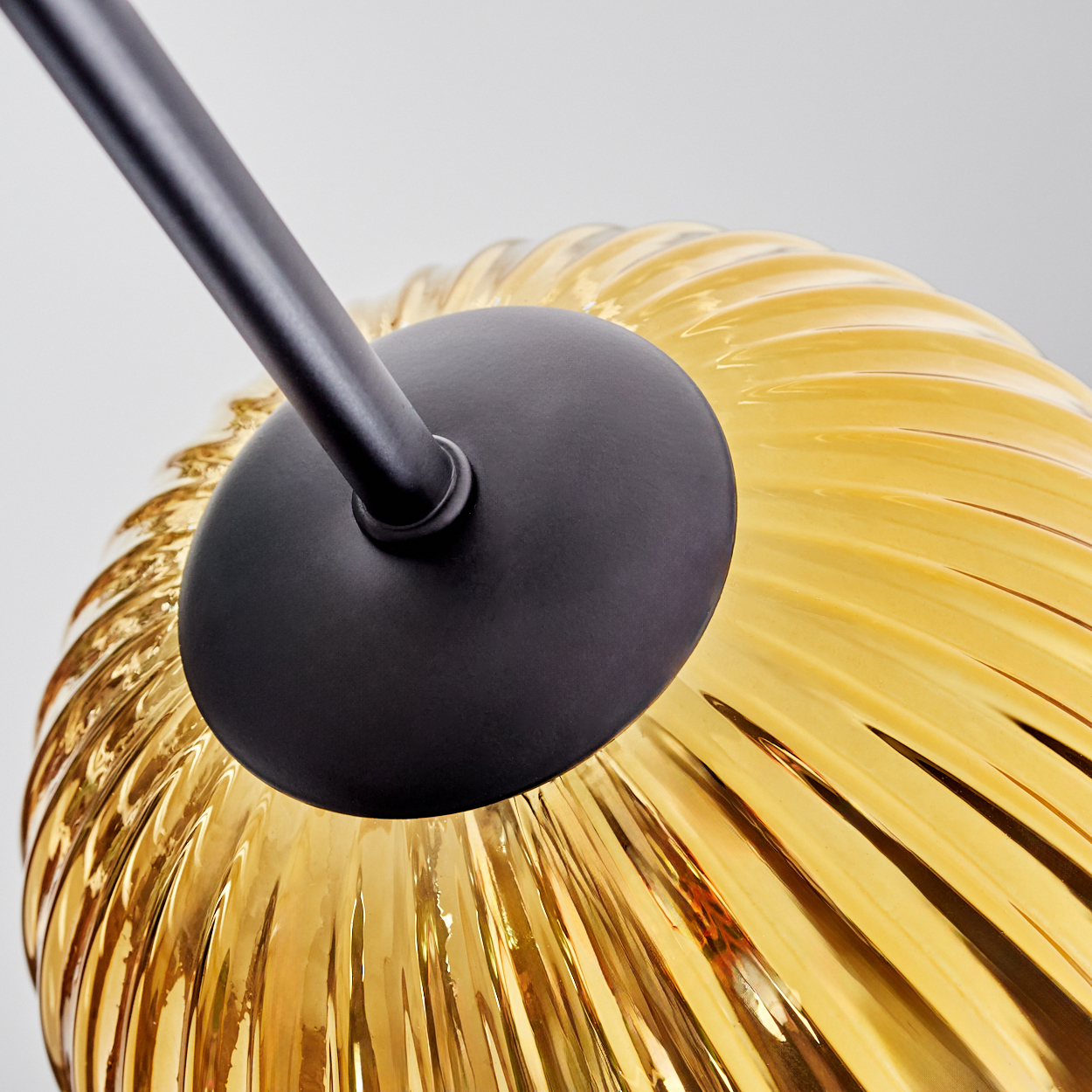 Nahaufnahme einer Lampe. Mit schwarzem Arm und kreisförmiger schwarzer Basis. Der Schirm ist gelb, mit geripptem Design.