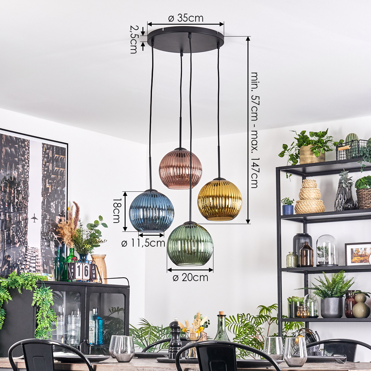Eine Pendelleuchte mit vier farbigen Glasschirmen hängt über einem Esstisch. Der Raum hat ein schwarzes Metallregal mit Pflanzen.
