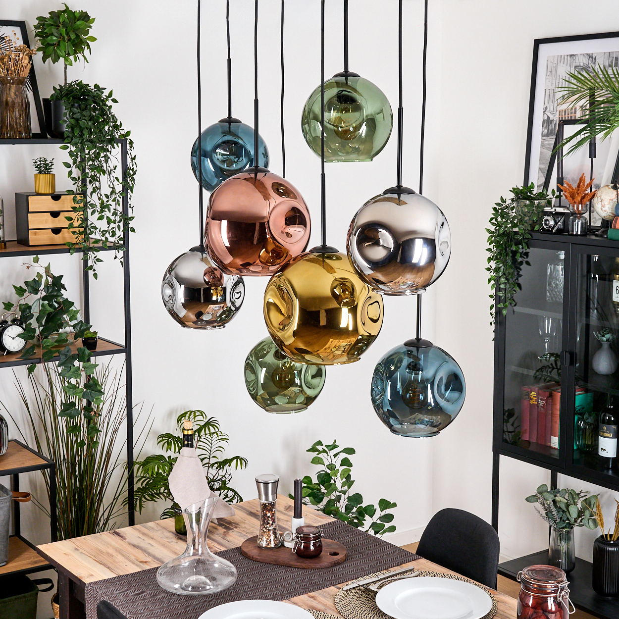 Esszimmer mit bunten Glaskugelleuchten. Holztisch mit Tellern und Dekanter.