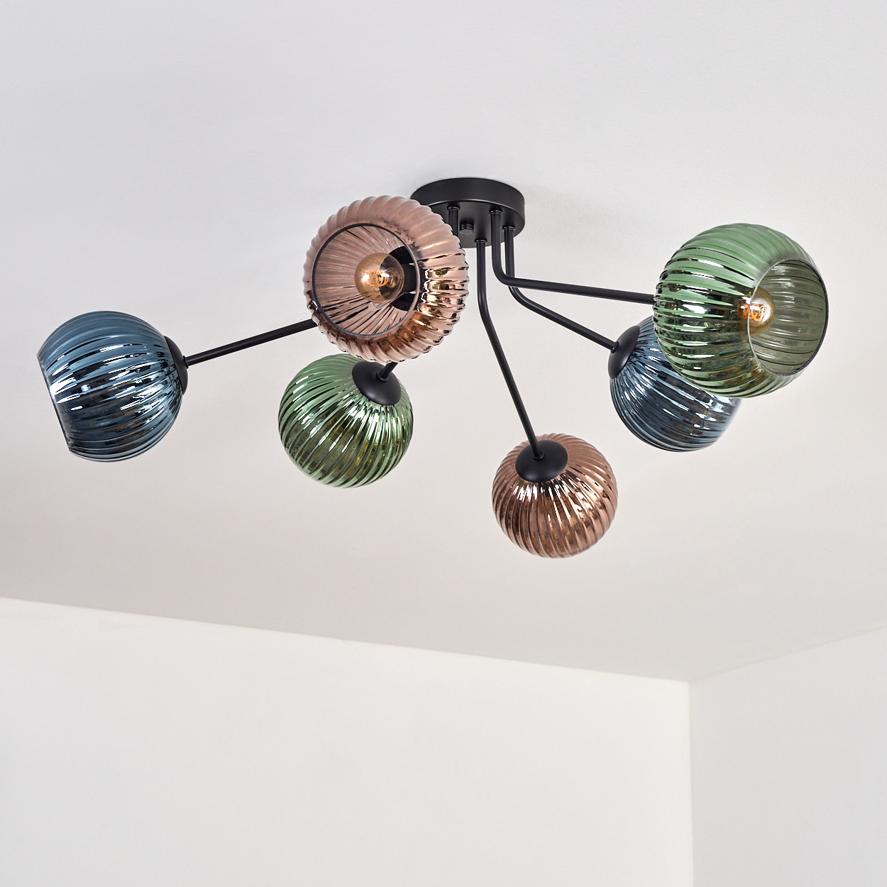 Deckenlampe mit schwarzen Armen und Glasschirmen in Grün, Blau und Kupfer, mit sichtbaren Glühbirnen.