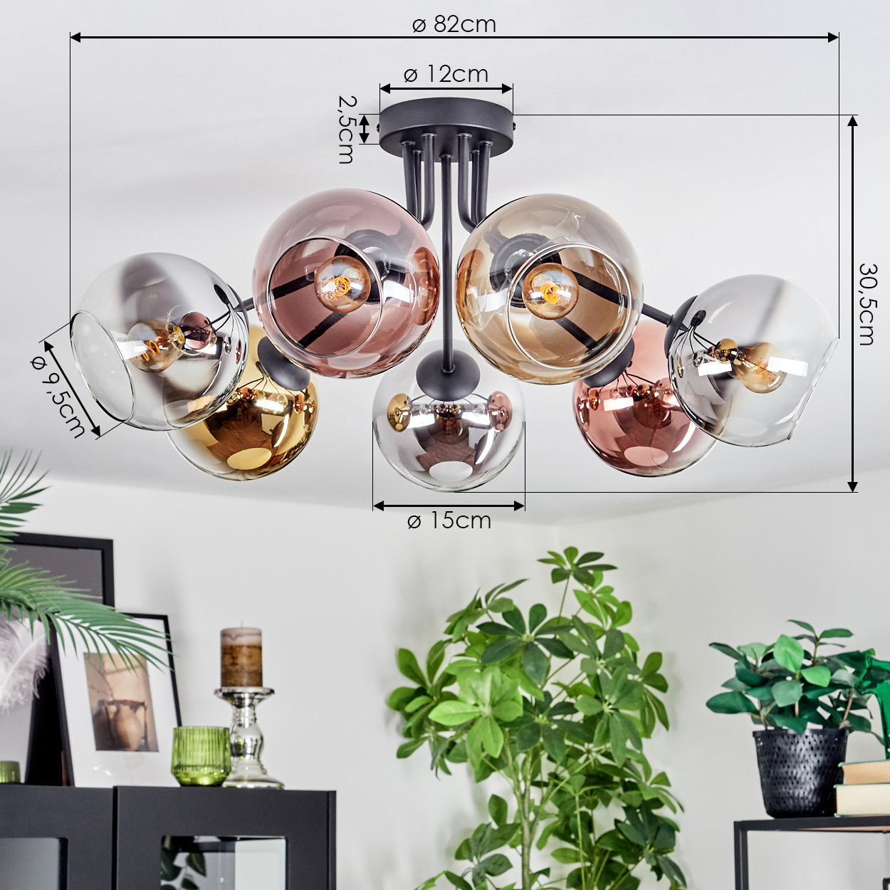 Deckenlampe mit Glaskugeln. Schwarze Halterung, mit Maßen. Pflanzen und Möbel im Hintergrund.
