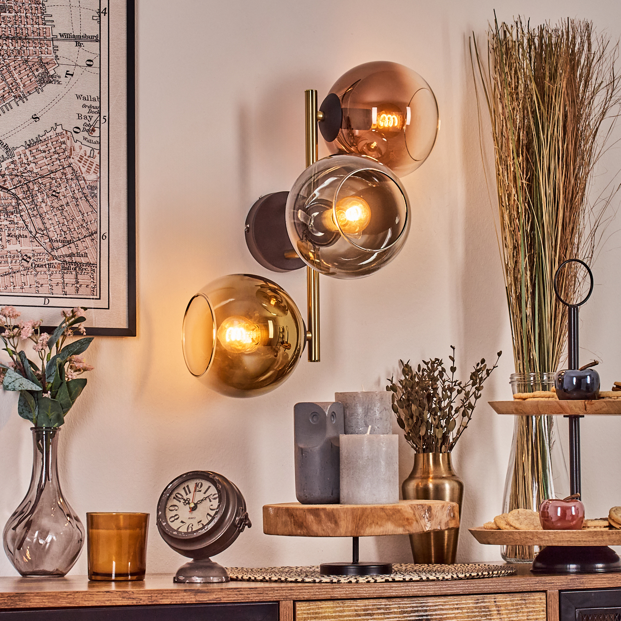 Ein Raum mit einer Wandlampe, einer Uhr, Kerzen und Dekorationen auf einem Holzregal. An der Wand hängt eine Karte.