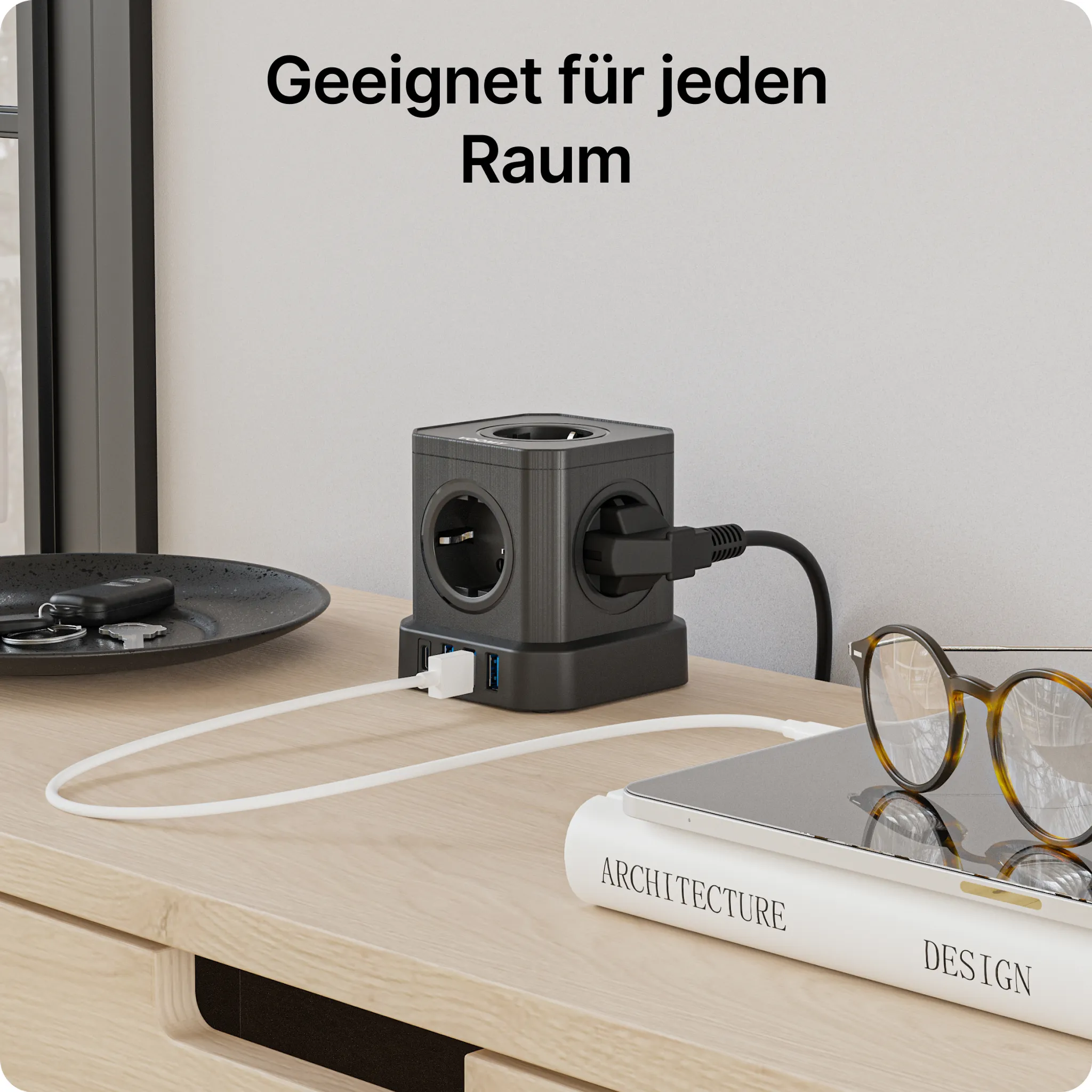 Ein schwarzer Steckerblock mit Steckdosen und USB-Anschlüssen steht auf einem Holzschreibtisch. Text: 'Geeignet für jeden Raum'.