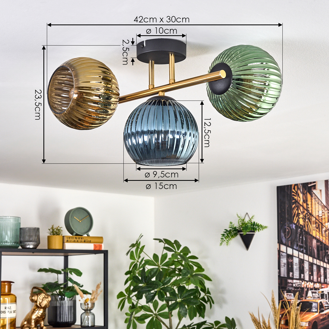 Eine moderne Deckenlampe mit drei Glaskugeln in Gold, Blau und Grün. Maße sind auf dem Bild markiert. Darunter ein Regal.