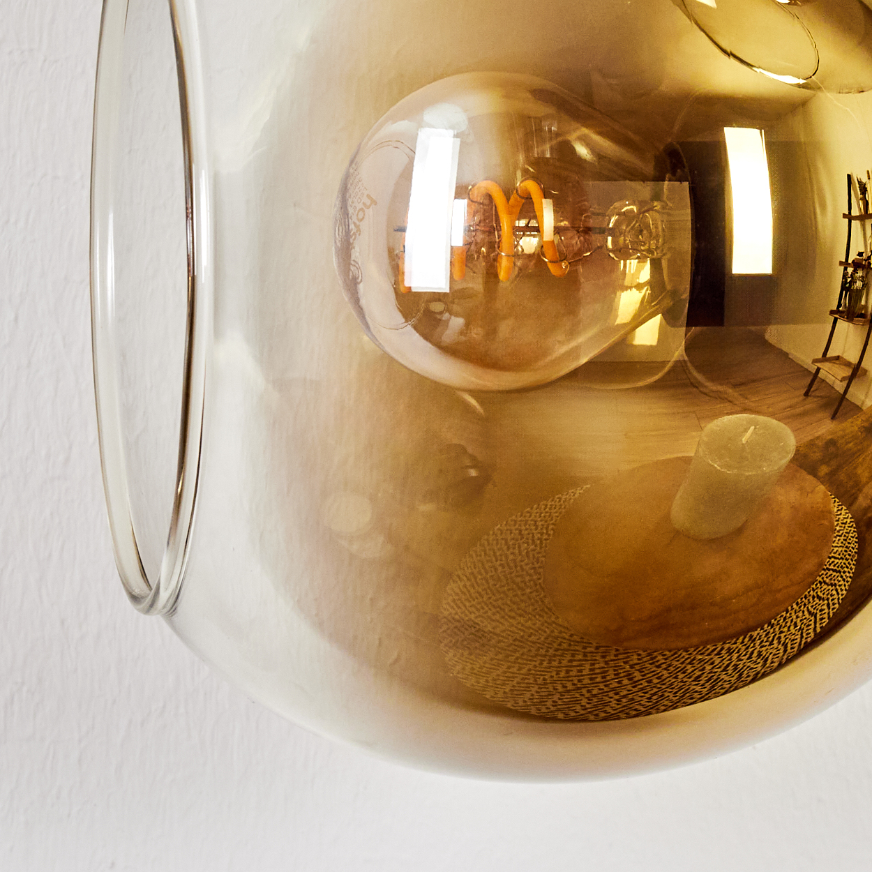 Eine dekorative Glaskugel mit Glühbirne, Kerze und gewebter Matte. Reflektierender Raum mit kleinem Regal.