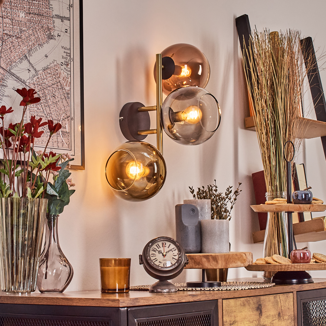 Eine dekorative Szene mit Wandlampe, Uhr, Blumen und Ornamenten auf einem Holzschrank, mit Karte und Dekorationsartikeln.