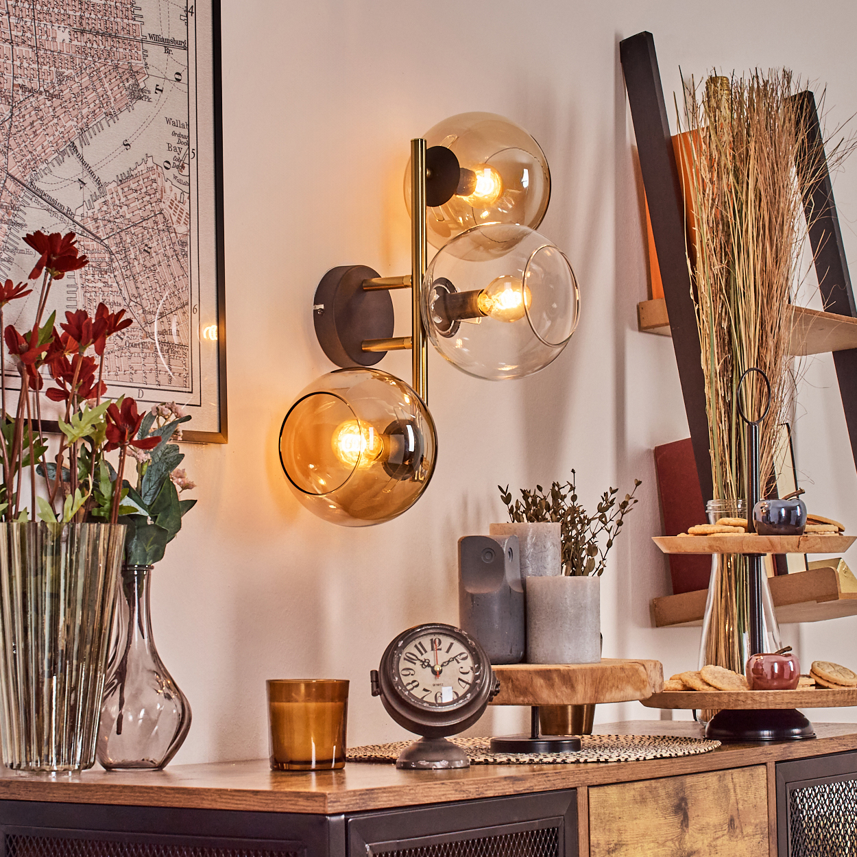 Ein Raum mit Lampe, Karte, Vasen mit Blumen, Uhr und dekorativer Leiter. Die Lampe hat drei Glaskugeln.