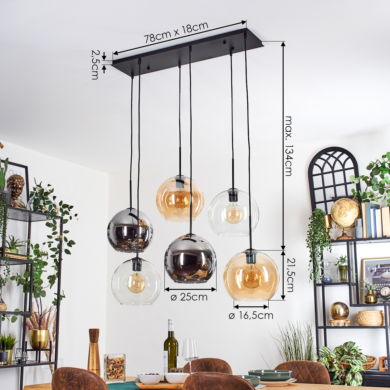 Ein modernes Esszimmer mit einem schwarzen Kronleuchter. Der Kronleuchter hat Glaskugeln. Ein Holztisch ist mit Tellern und Gläsern gedeckt.