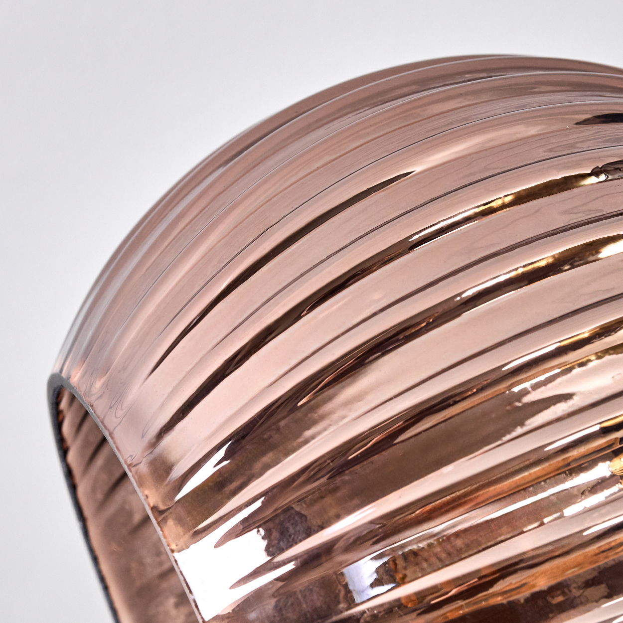 Nahaufnahme eines roségoldenen, geriffelten, gebogenen Objekts. Das Licht reflektiert und erzeugt Glanzlichter. Der Hintergrund ist weiß.