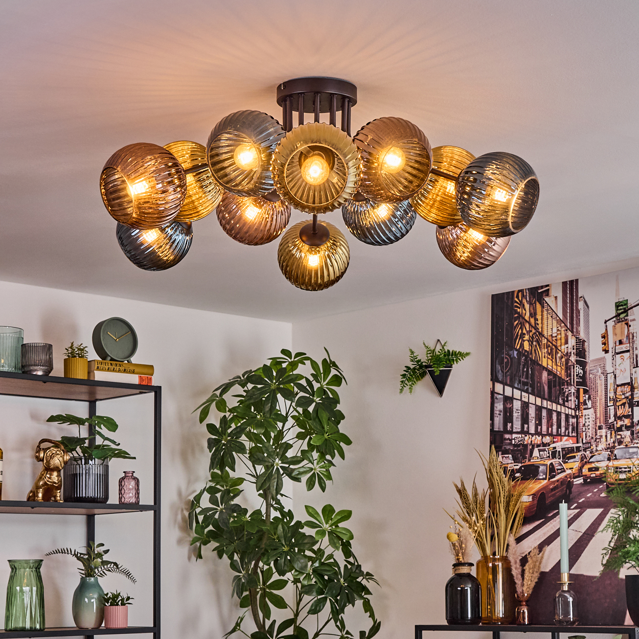 Moderne Deckenlampe mit mehreren Kugelleuchten. Eine Pflanze, Regale mit Dekoration und ein Stadtlandschaftsbild im Hintergrund.
