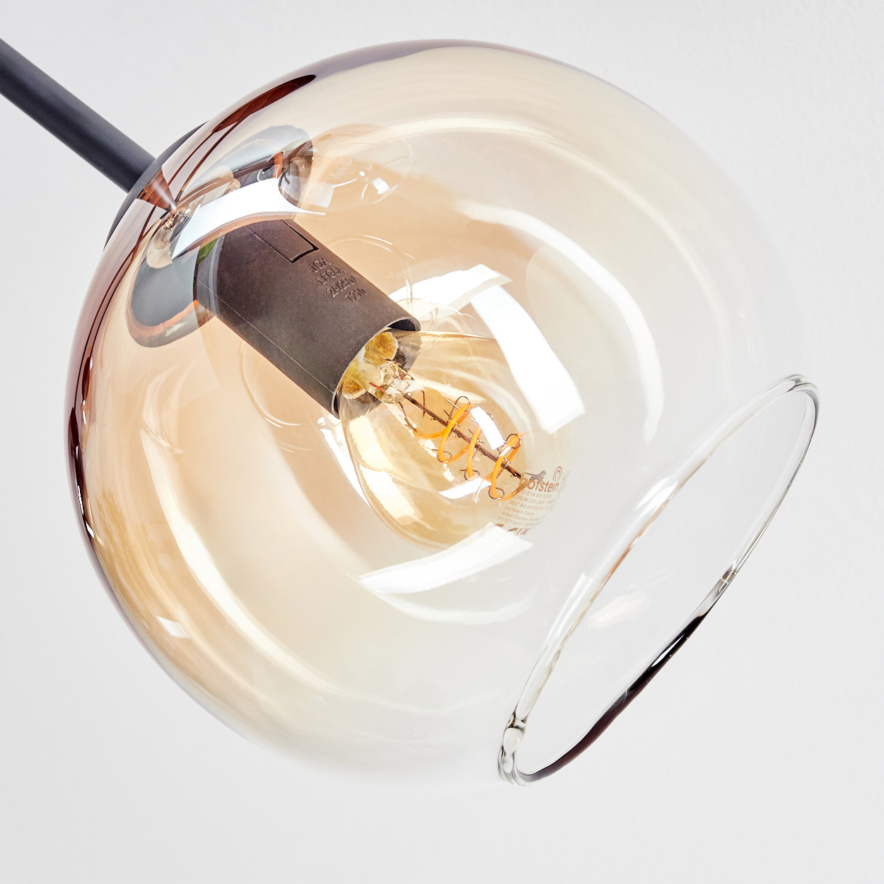 Nahaufnahme einer Glühbirne in einem Glaskolben. Der Globus ist klar mit einem braunen Farbton. Die Glühbirne leuchtet.