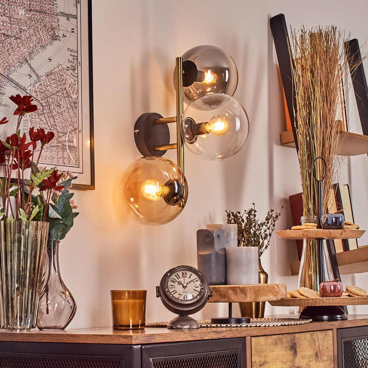 Ein Raum mit einer Wandlampe, einer Uhr und einem Tisch mit Dekorationen. An der Wand hängt eine Karte. In einer Vase stehen Blumen.