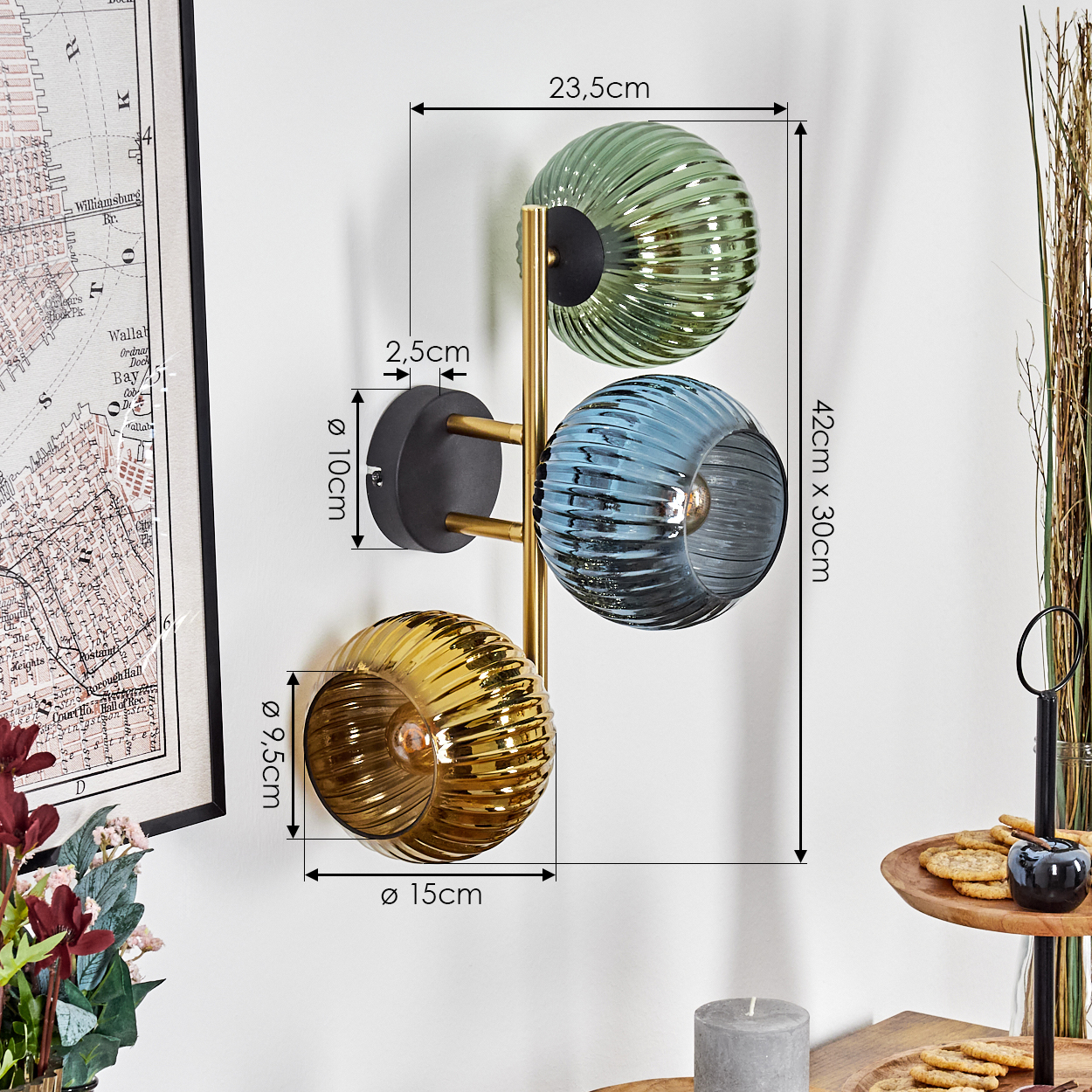 Eine Wandlampe mit drei Glaskugeln in Grün, Blau und Gold. Maße sind angegeben. Weitere Dekorationen umfassen eine Karte und ein kleines Holztablett.