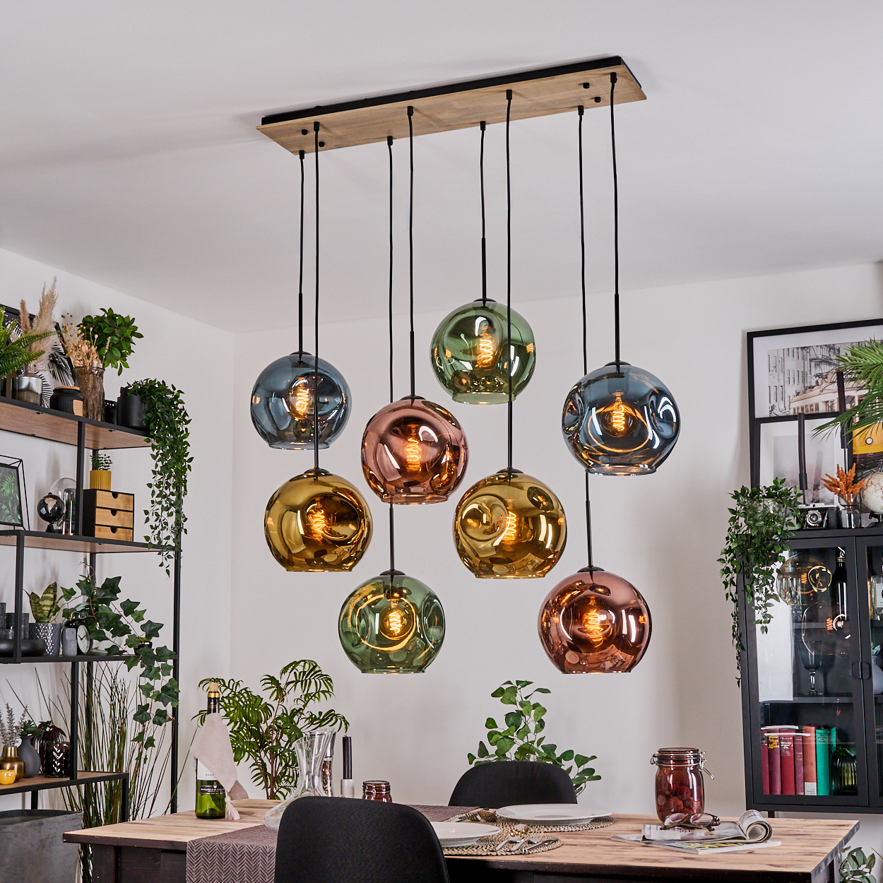 Ein Esszimmer mit bunten Glaskugellampen. Ein Holztisch ist mit Tellern gedeckt, und ein dekoratives Regal befindet sich im Hintergrund.