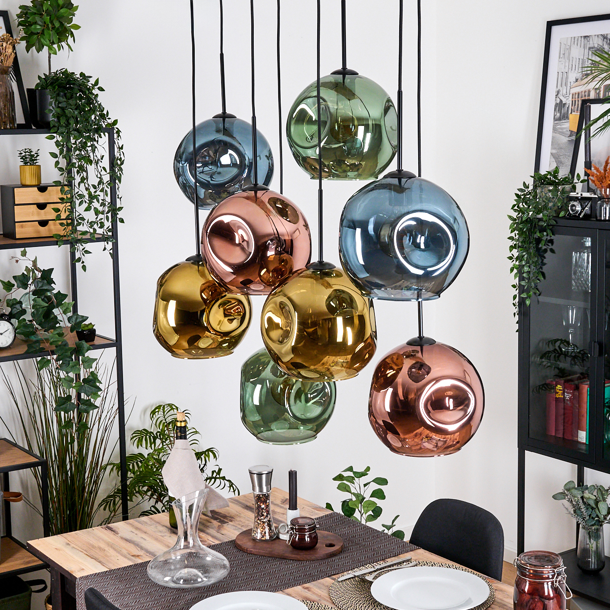 Esszimmer mit Holztisch, bunten Kugelleuchten. Pflanzen und Dekoartikel umgeben den Tisch.