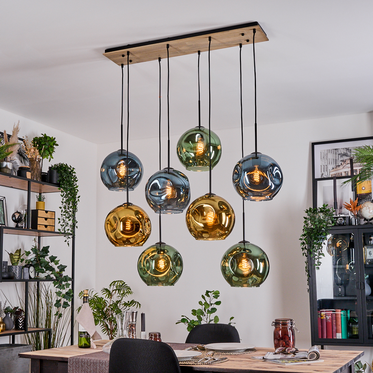 Esszimmer mit hängenden Glaslampen. Die Lampen sind in verschiedenen Farben gehalten, auf dem Tisch steht ein Einmachglas.