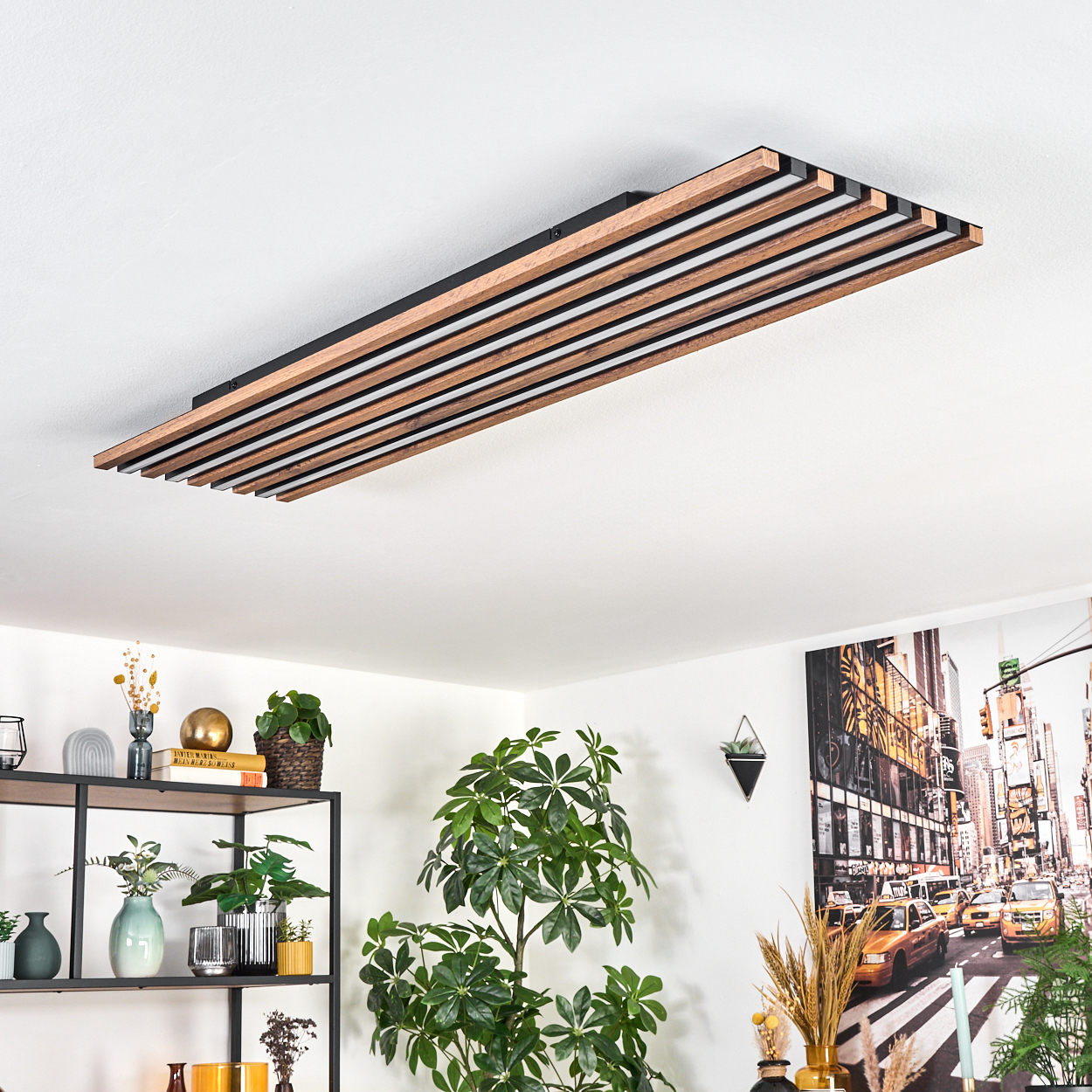 Eine moderne Deckenlampe mit Holzlatten, Pflanzen und ein Stadtbild-Gemälde schaffen ein stilvolles Interieur.