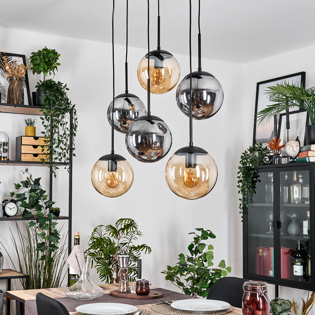 Esszimmer mit hängenden Kugelleuchten. Tisch mit Pflanzen und Dekoration. Regale und Schrank mit Gegenständen.