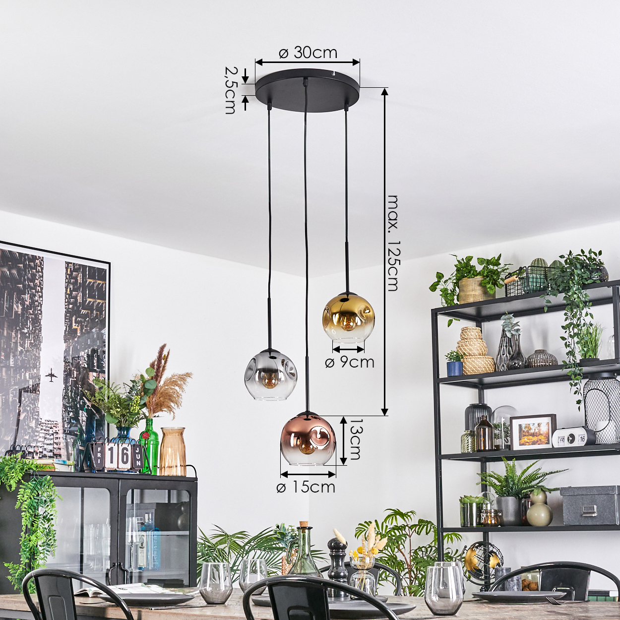 Drei Pendelleuchten mit Glaskugeln hängen über einem Holztisch. Pflanzen und Dekorationen stehen auf einem Regal im Hintergrund.