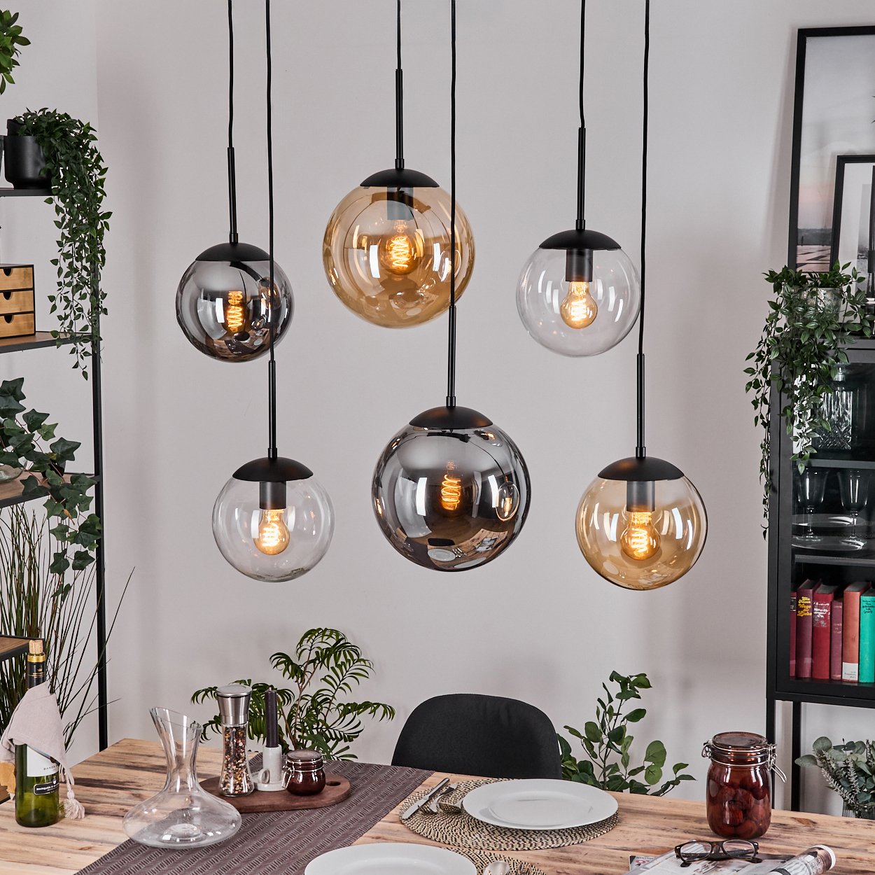 Esszimmer mit sechs Kugelleuchten, Holztisch mit Tellern und Pflanzen auf Regalen.