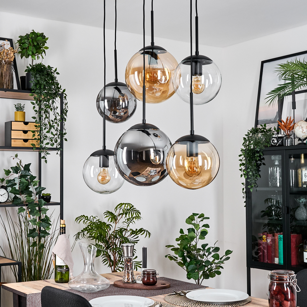 Esszimmer mit Hängekugelleuchten, Pflanzen, Tischdeko und Dekoelementen. Reflektierende und transparente Glaskugeln.