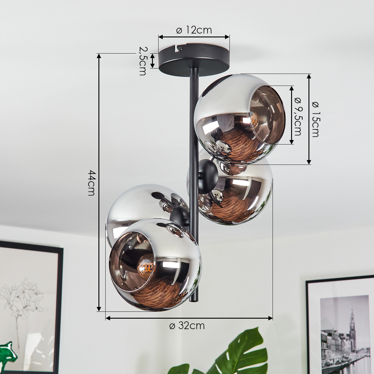 Eine moderne Deckenlampe mit drei kugelförmigen Chrom-Lampenschirmen, schwarzem Metallrahmen. Maße sind angegeben. Der Hintergrund ist weiß.