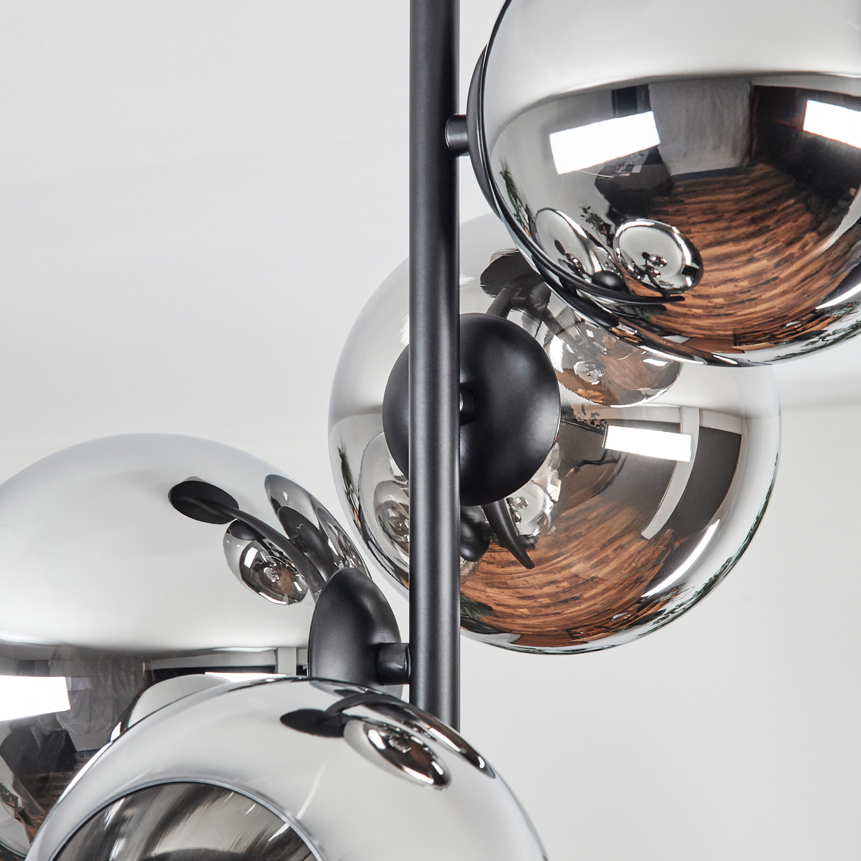 Nahaufnahme einer modernen Lampe mit mehreren reflektierenden, kugelförmigen Silberschirmen. Schwarze Stützen und weißer Hintergrund.