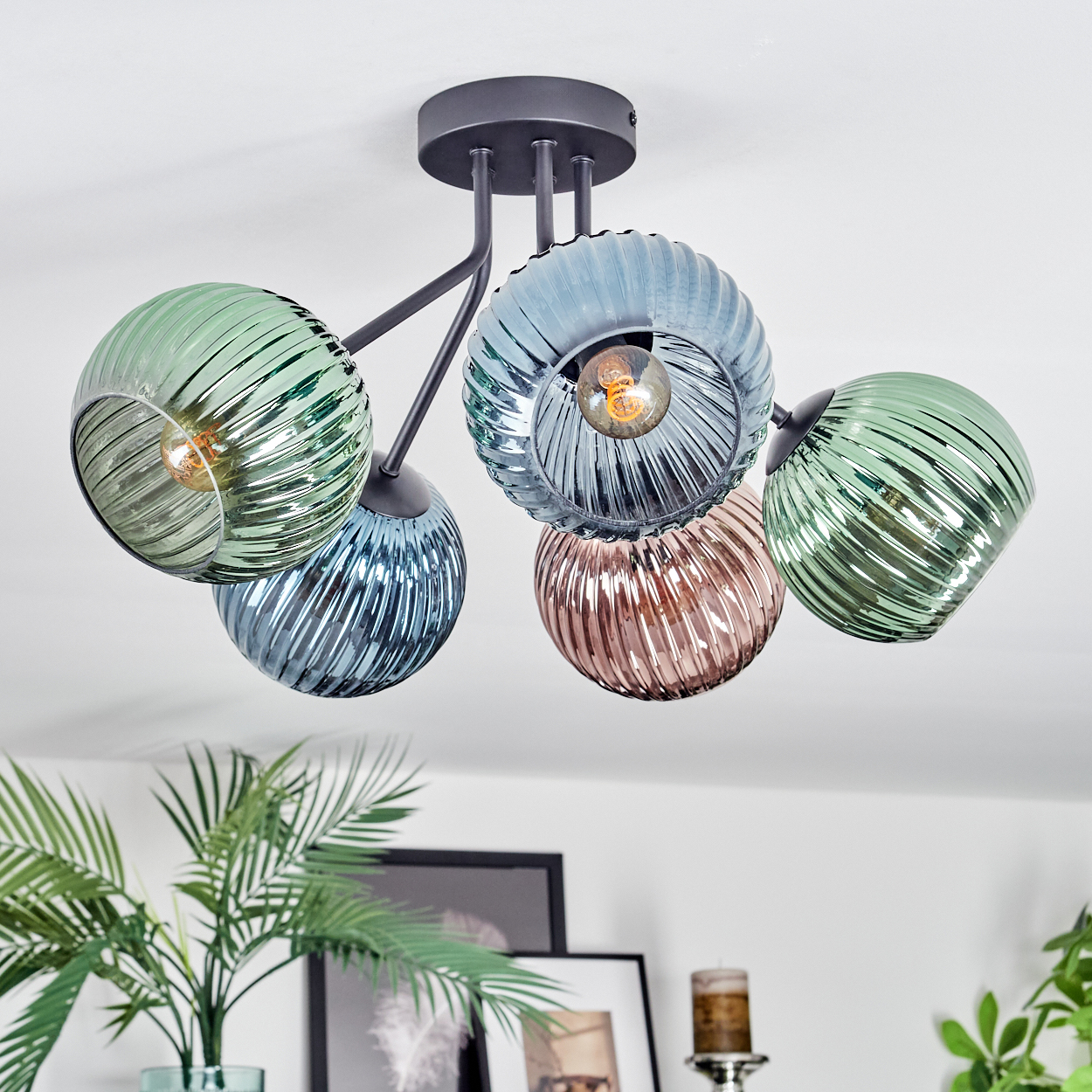 Eine moderne Deckenlampe mit fünf farbigen Glaskugeln, verschiedenen Farben, schwarzen Metallarmen und weißem Deckenhintergrund.