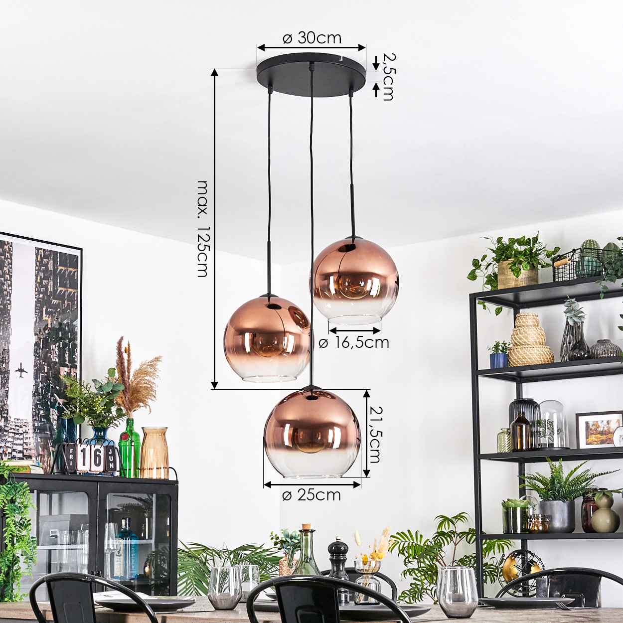 Drei kupferfarbene Pendelleuchten hängen von einer schwarzen Deckenplatte. Abmessungen sind beschriftet. Pflanzen und ein Esstisch sind sichtbar.