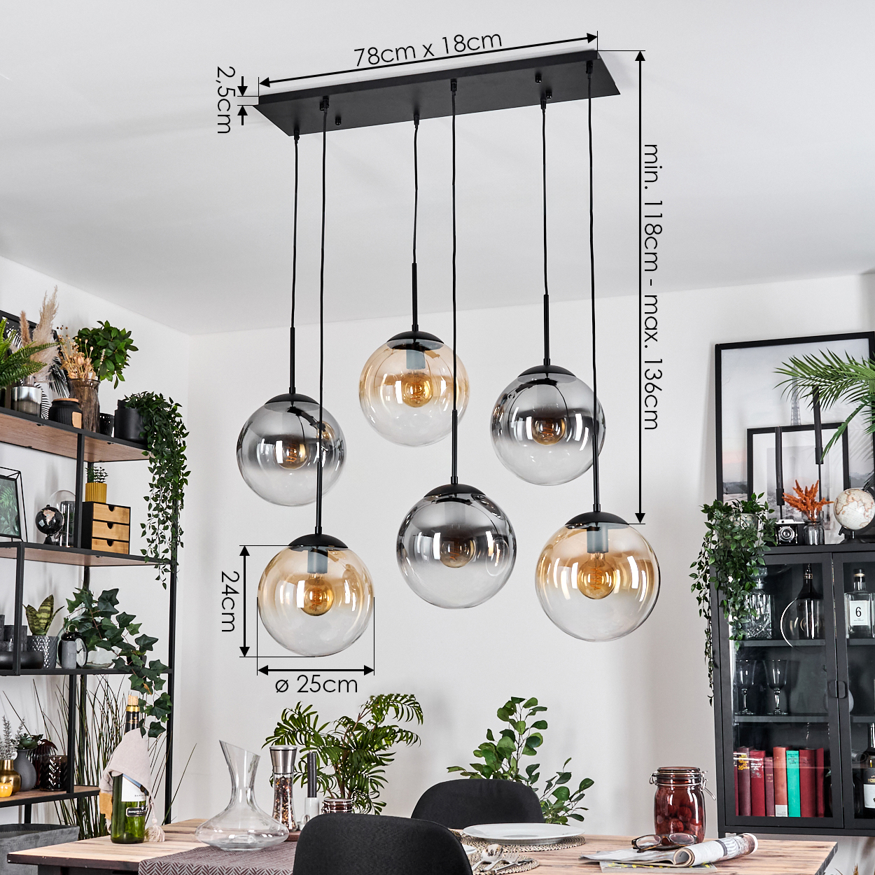 Esszimmer mit Kronleuchter. Der Kronleuchter hat 6 Glaskugelleuchten. Ein Holztisch und schwarze Stühle sind im Vordergrund.